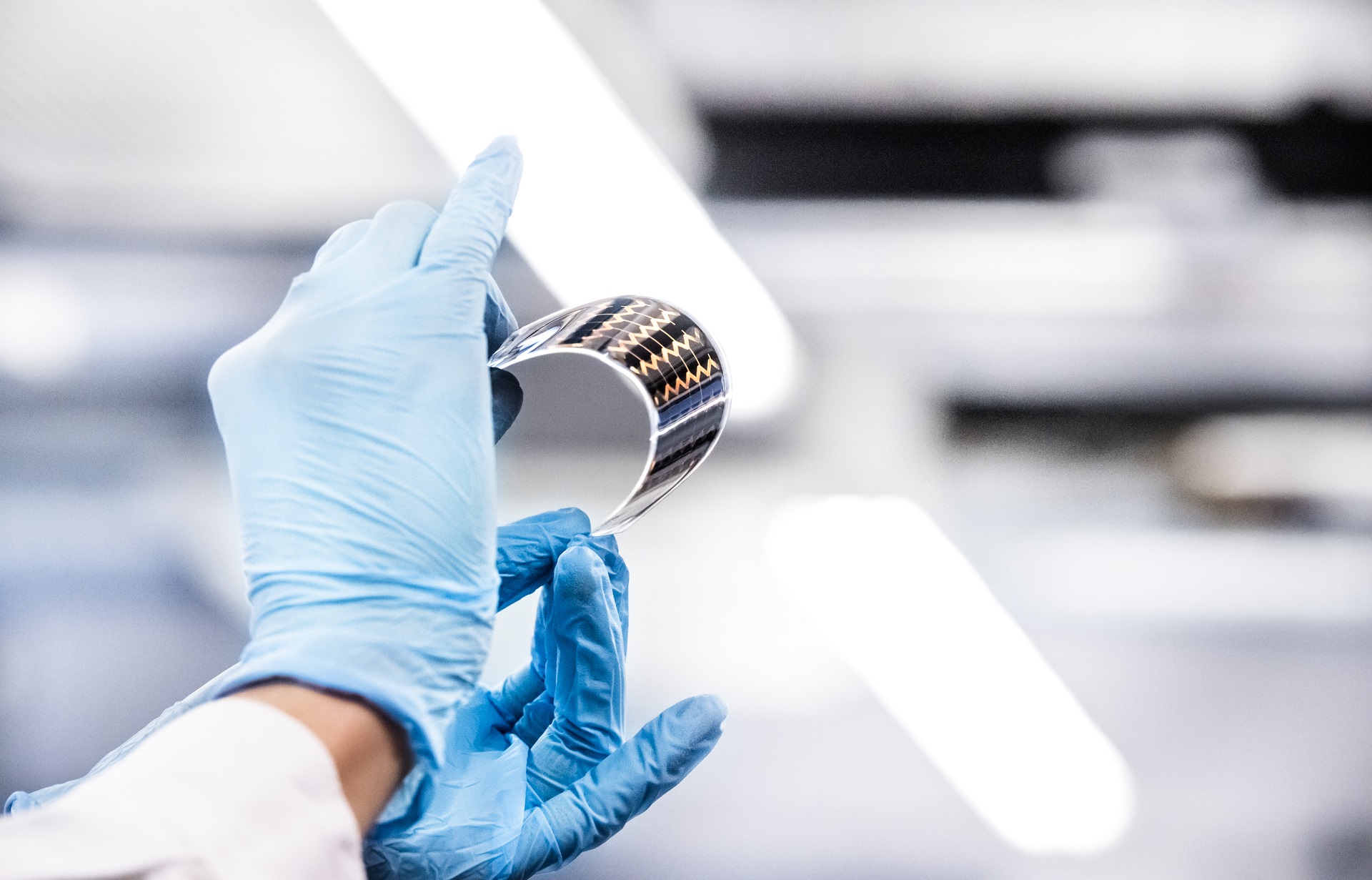 Dłonie w rękawiczce do badań trzymające kawałek czarno-złotej folii