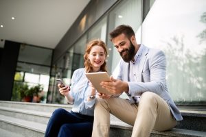 Młodzi ludzie siedzą na schodach i trzymają w ręku tablet