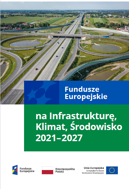Duża droga szybkiego ruchu i rozwidlenia w dwie strony. W tle domki i pola.