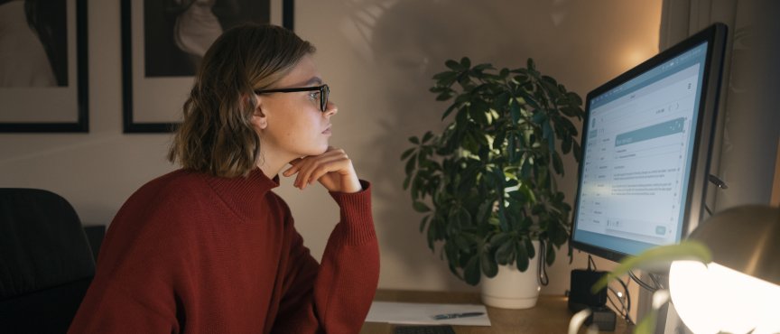 kobieta w okularach siedzi przed ekranem komputera