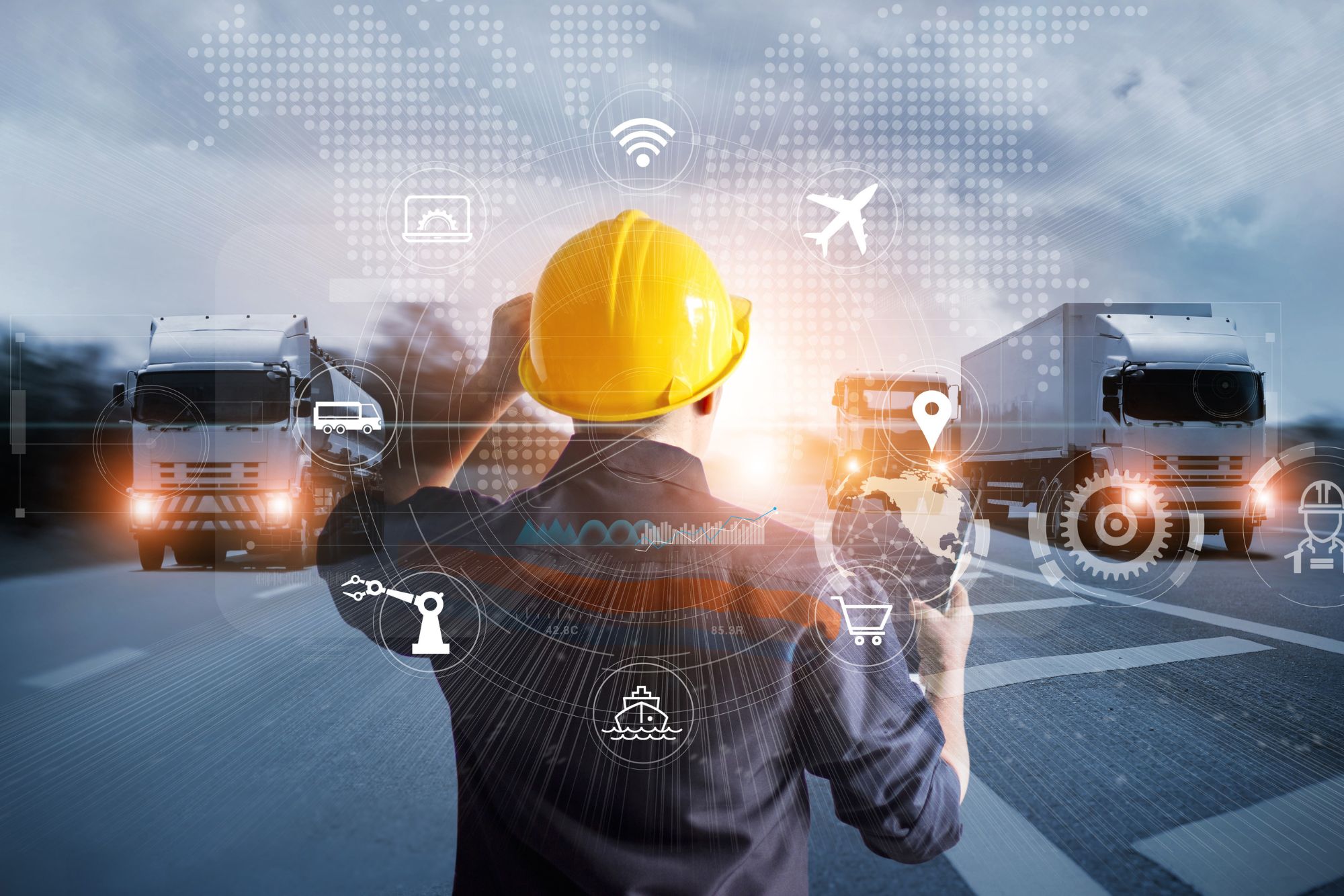 Pracownik w kasku ochronnym stoi na środku autostrady, po obu stronach jadą ciężarówki 