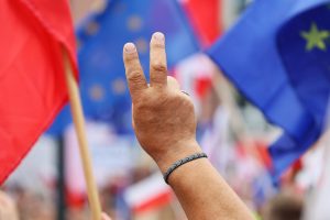 Ręka na tle flag Polski i Unii Europejskiej, fot. FotoDax – Adobe Stock
