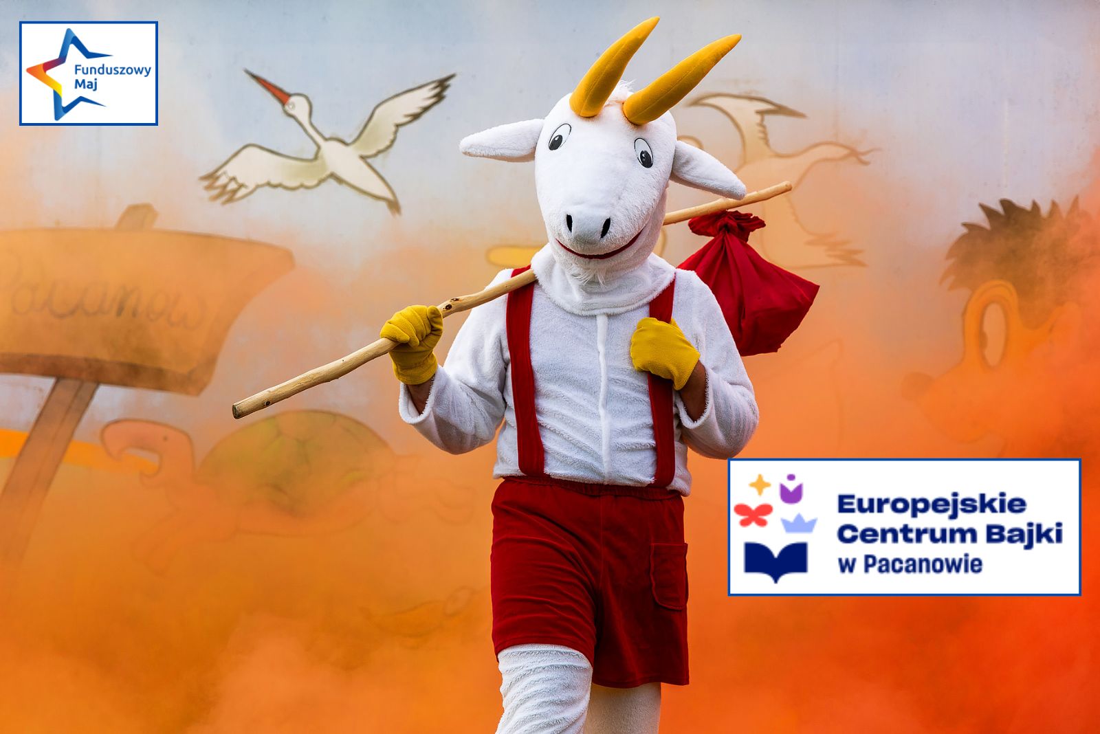 Człowiek w przebraniu Koziołka Matołka na tle pamarańczowego dymu, logo Funduszowy Maj, logo Europejskie Centrum Bajki w Pacanowie