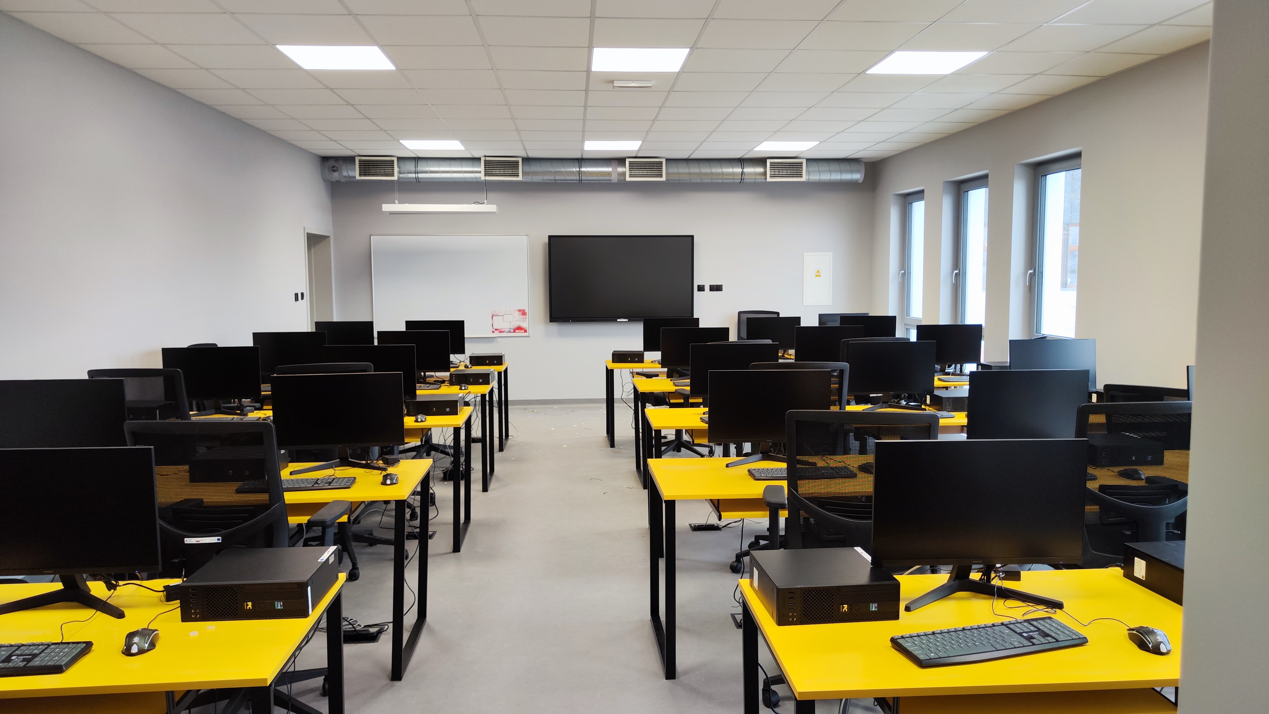 sala szkoleniowa z ławkami i komputerami 