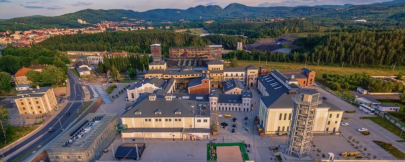 Widok z lotu ptaka na kompleks przemysłowo-turystyczny w Starej Kopalni, otoczony lasami i górami.