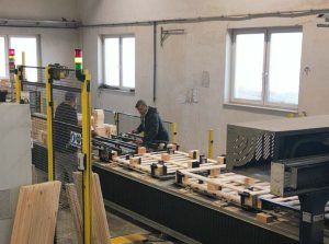 ramię robota unosi drewnianą paletę