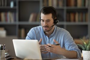 Zdjęcie mężczyzny z laptopem biorącego udział w szkoleniu online.