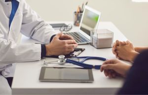 Zdjęcie przedstawia przychodnię lekarską, pacjentów i lekarza